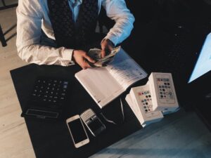 A man counting money with a notebook and books